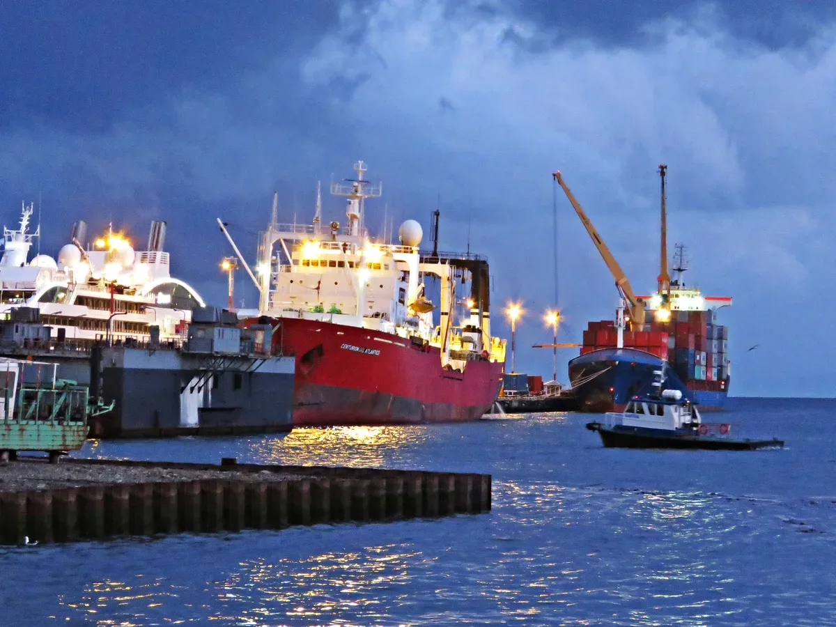 Ships and cranes of the working harbor of Ushuaia at night under a deep blue sky, Argentina